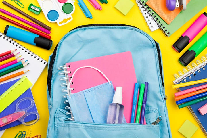 Maleta escolar con materiales escolares a su alrededor